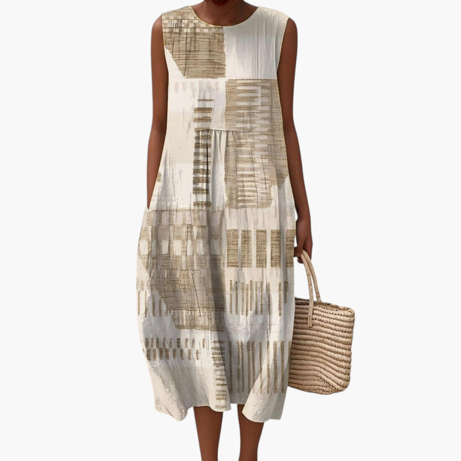 My Store 4 Helena mouwloze zomerjurk met abstracte print in zandkleur, gedragen op een strand.