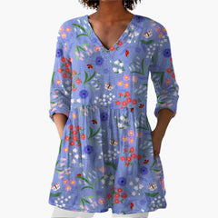 My Store 4 Josie lange blouse met V-hals, blauwe stof met kleurrijk bloemen- en insectenpatroon en zakken.