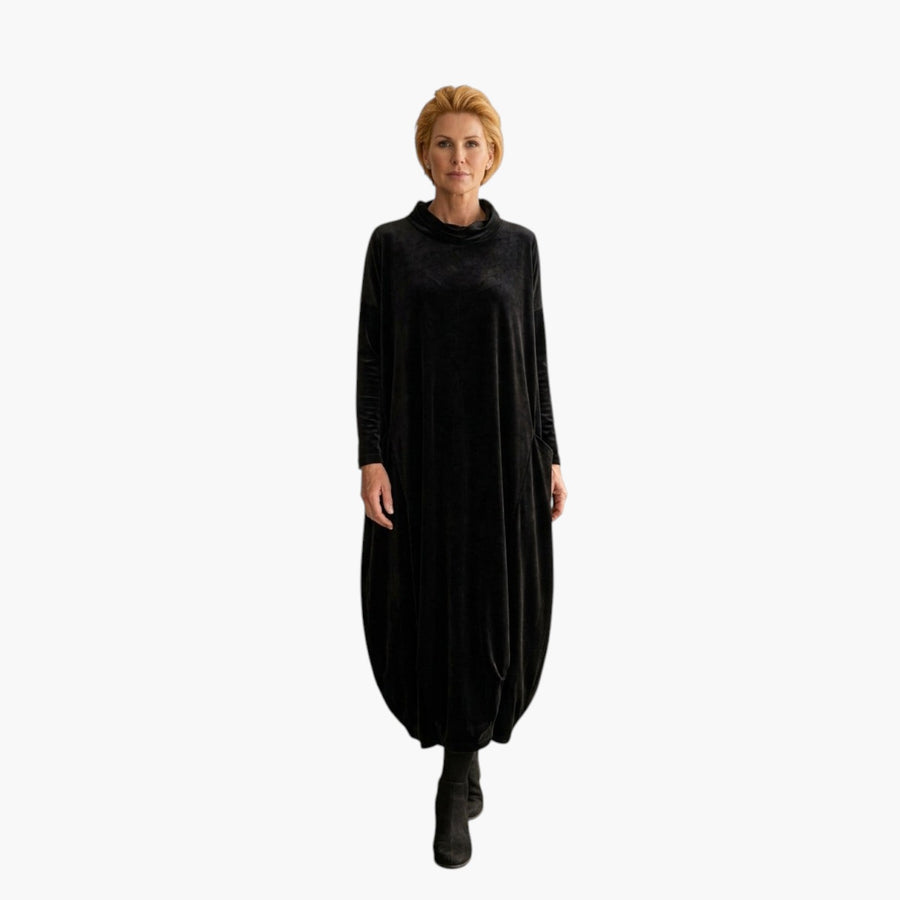 My Store 4 Leona fluwelen maxi-jurk in zwart met opstaande kraag en zakken, gedragen door een vrouw in een interieur.