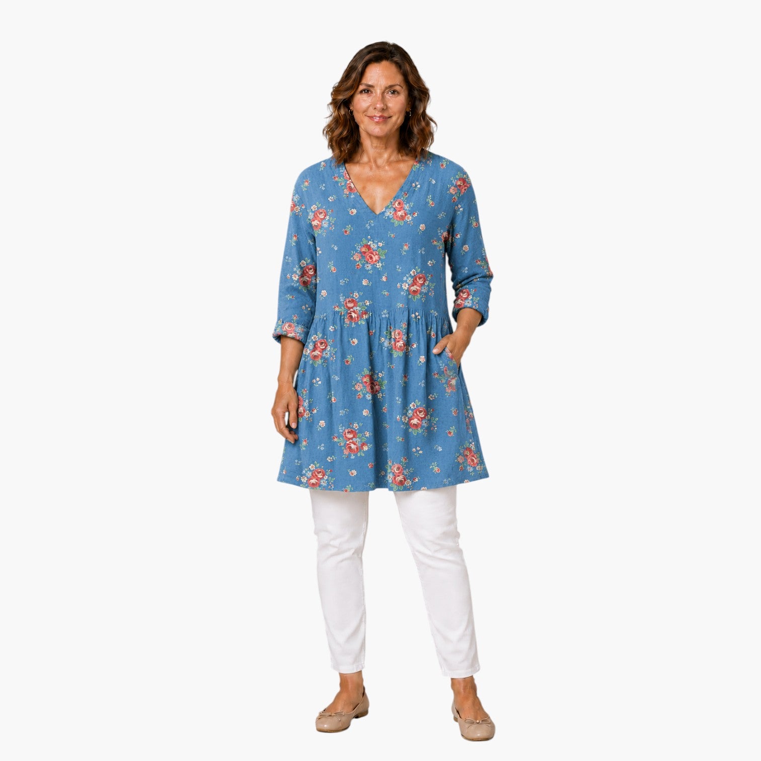 Model draagt een My Store 4 Lucia blouse met blauwe bloemenprint, V-hals en lange mouwen, gecombineerd met witte broek.