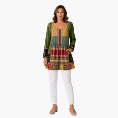 Model draagt My Store 4 Melody lange blouse met V-hals, kleurrijk patroon en zakken, gecombineerd met witte broek.