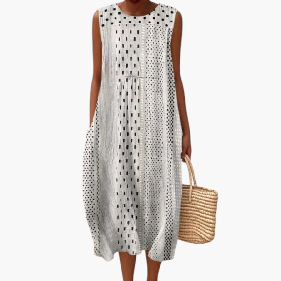 My Store 4 Paige Polka Midi Dress in zwart-wit met mouwloos ontwerp en ronde hals, gedragen op een strand.