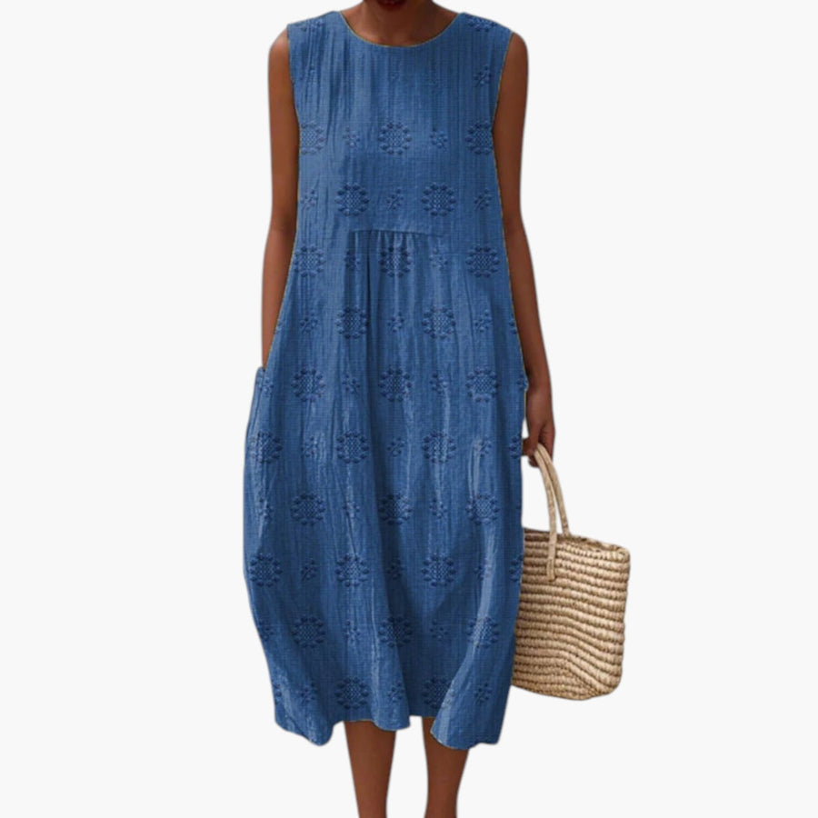 My Store blauwe mouwloze midi-jurk met geborduurd patroon en zakken, gedragen op een zandstrand.